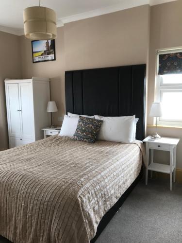 a bedroom with a large bed with a large black headboard at Number 29 - Only Adults in Shanklin