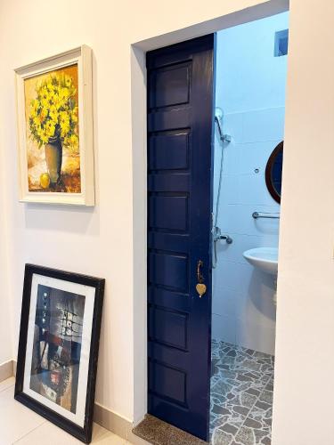 a blue door in a bathroom with a picture at Thiên Trúc Ecohome, đồi Từ Hiếu in Thôn Dương Xuân Hạ