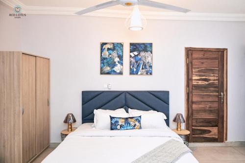 a bedroom with a bed and two paintings on the wall at Charming Rooftop Apartments with Great view & Free Strong Wi-Fi - 40percent Long-stay Disc- Red Lotus Oasis in Accra