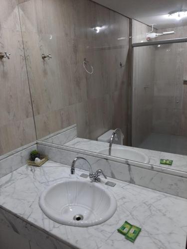 a bathroom with a white sink and a shower at Apartamento confortável in Goiânia