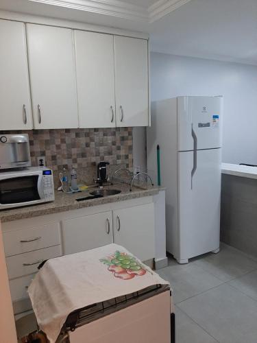 a kitchen with white cabinets and a white refrigerator at Apartamento confortável in Goiânia