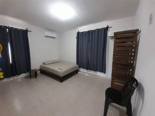 Zimmer mit einem Bett, einem Stuhl und Vorhängen in der Unterkunft Casa Privada Palmas 10 con Alberca in Kanasín