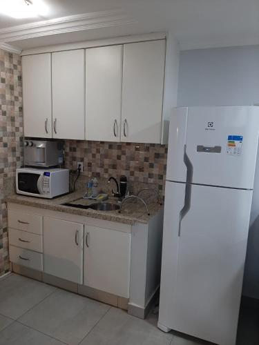 a kitchen with white cabinets and a white refrigerator at Apartamento confortável in Goiânia