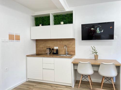 a kitchen with white cabinets and a table and chairs at Under Castle Apartment in Ljubljana