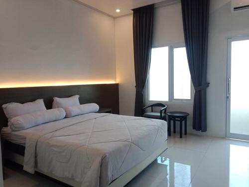 a bedroom with a large white bed and a window at Genio Syariah Hotel Solo in Tjolomadu