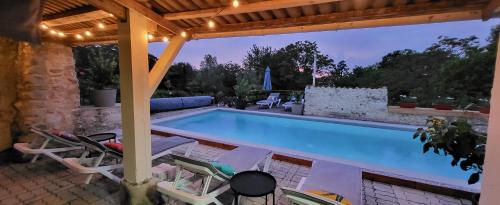 - une piscine avec des chaises et une pergola dans l'établissement La Marguerite, à Brossac