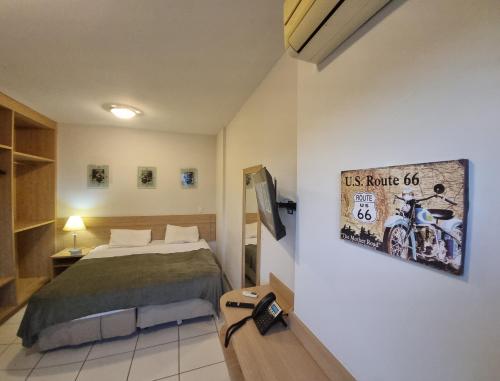 a bedroom with a bed and a picture of a motorcycle on the wall at Flat 317 Golden Dolphin Express in Caldas Novas
