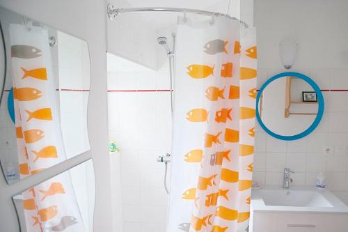 La salle de bains est pourvue d'un rideau de douche avec des poissons. dans l'établissement Le gîte des Algues, à Séné