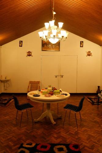 a room with a table and chairs and a chandelier at The Green Casa - Families Only in Ooty
