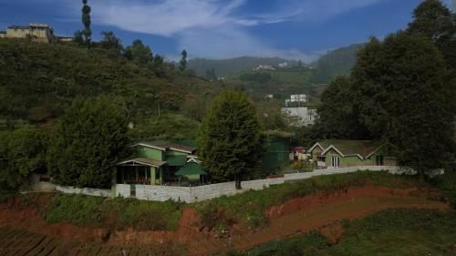 a house on a hill with a fence and trees at The Green Casa - Families Only in Ooty