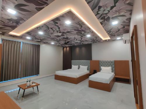 a hotel room with two beds and a table at Hotel Pride Of Chittor in Chittaurgarh