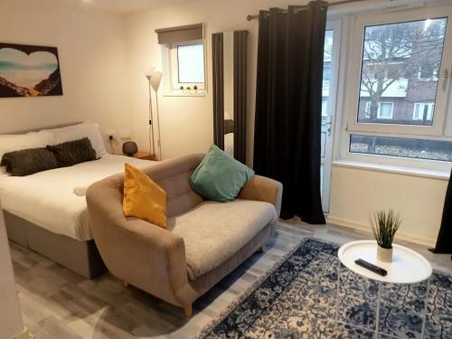 1 dormitorio con cama, sofá y ventana en Studio apartment in London, Bethnal Green en Londres