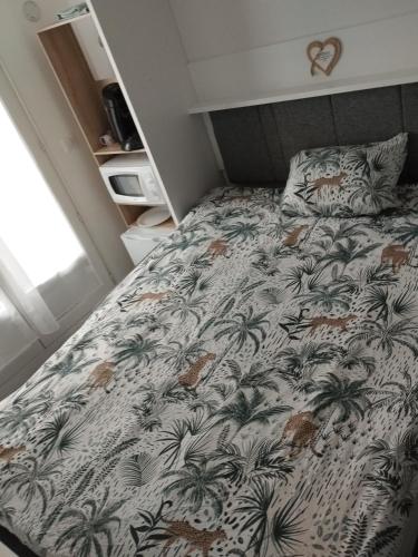 1 dormitorio con cama con motivos de palmera en Chambre fonctionelle, en Gisors