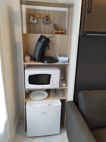 eine Mikrowelle auf einem Regal neben einem Stuhl in der Unterkunft Chambre fonctionelle in Gisors