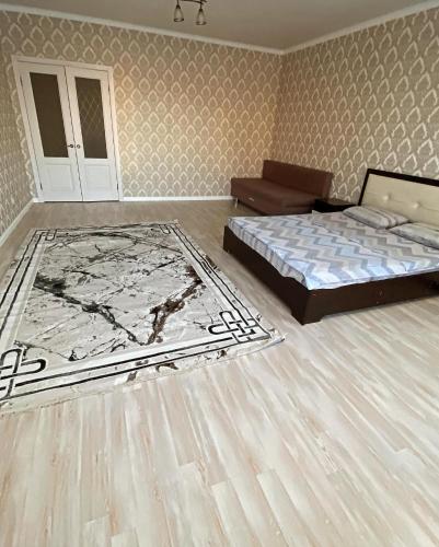 a bedroom with a bed and a rug on the floor at APARTAMENT в мкр Батыс-2 в комфортном ЖК Нектар in Aktobe