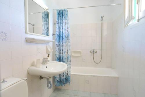 uma casa de banho com um lavatório, uma banheira e um WC. em Spiros Saint Stephanos em Ágios Stéfanos