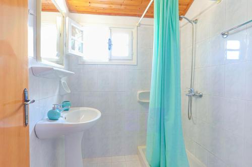 a white bathroom with a sink and a shower at Anna Apartment Agios Stephanos in Ágios Stéfanos