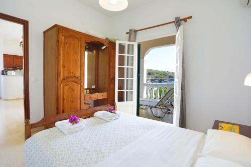 1 dormitorio con 1 cama con sábanas blancas y balcón en Evanna House in Saint Stephanos, en Ágios Stéfanos
