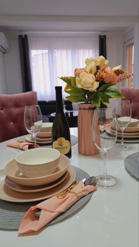 a table with plates and glasses and a vase of flowers at Maja 2 in Ruma