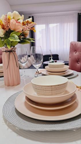 a table with plates and glasses and a vase of flowers at Maja 2 in Ruma