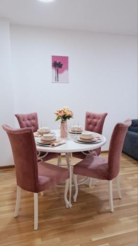 a white dining room table with chairs and a white wall at Maja 2 in Ruma