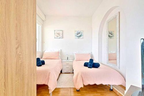 a bedroom with two beds with pink sheets and a mirror at Villa Marite - 4 bed/ 2 bath - own private pool in Fuengirola
