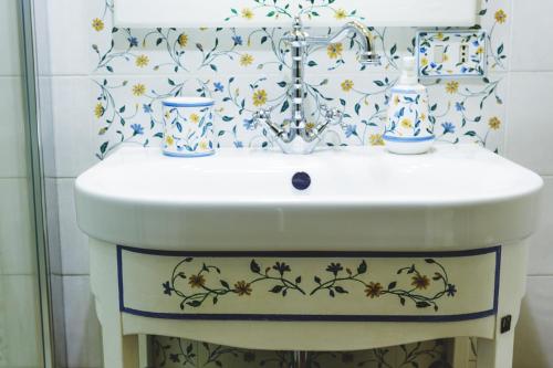 a bathroom sink with a floral pattern on the wall at Bosco D'Olmi Country House in SantʼAndrea del Garigliano
