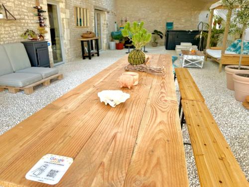 a wooden table in the middle of a living room at Le Grenier - Gîte de Charme La Rochelle in Saint-Médard-dʼAunis