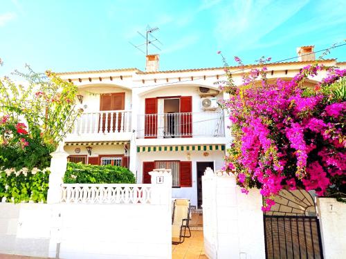 ein weißes Haus mit rosa Blumen davor in der Unterkunft Maravilloso Bungalow in Gran Alacant