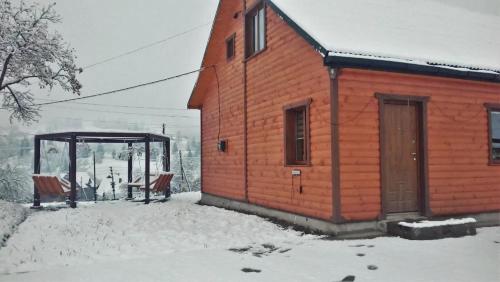 um edifício de madeira com um abrigo na neve em Cottage Ozerniy em Lazeshchyna