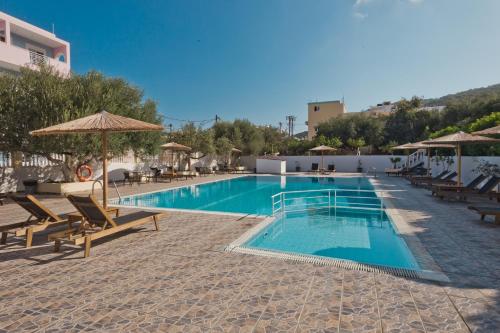 una piscina con sedie e ombrelloni in un resort di Regina Studios & Hotel a Karpathos