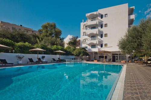 a swimming pool in front of a building at Regina Studios & Hotel in Karpathos Town