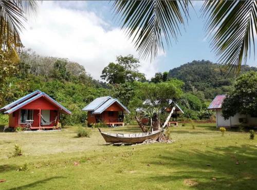 een groep huizen en een boot in een veld bij Libong Garden Beach in Ko Libong