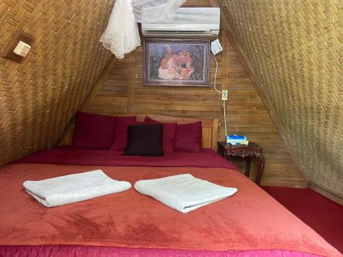 a bedroom with a red bed with two towels on it at Triangle House and hot spring in Kintamani