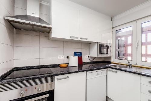 a white kitchen with white cabinets and a sink at Mia Guest House in Setúbal