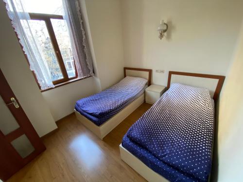 twee bedden in een kleine kamer met een raam bij Renovated One Bedroom in the Touristic Center of Yerevan in Jerevan