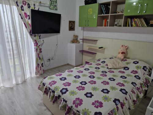 - une chambre avec un lit et une couverture fleurie dans l'établissement Casa din Izvor, à Tărlungeni