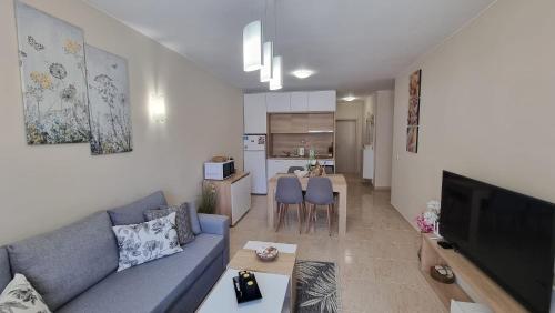 Sea Dreams Sunrise Apartment في سفيتي فلاس: غرفة معيشة مع أريكة زرقاء ومطبخ