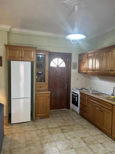 a kitchen with wooden cabinets and a white refrigerator at Ambracian Gulf Comfort House in Menídion