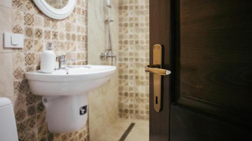 a bathroom with a sink and a toilet and a door at AristoCat Hotels Rasnov in Râşnov