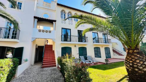 a building with a palm tree in front of it at Charming triplex T2 in the Old Village Vilamoura in Quarteira