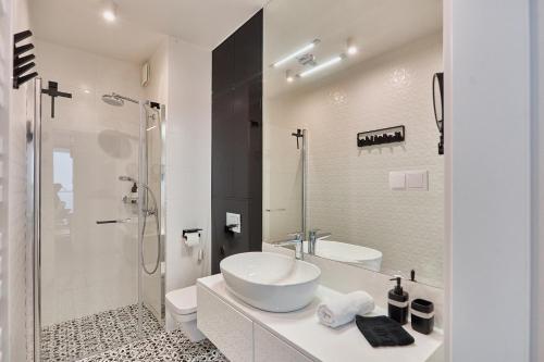 ein weißes Bad mit einem Waschbecken und einer Dusche in der Unterkunft Wave Panorama Apartment - Sea View&SPA in Misdroy