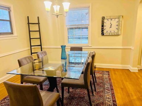 a dining room with a glass table and chairs and a clock at Lux 4 Bed Home w/ Parking Walk to Bethesda Metro! in Chevy Chase