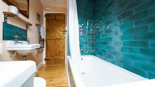 a bathroom with a tub and a sink and a toilet at Mwsogl - Luxurious Family Fishing Lodge Near Aberaeron With Private Fishing in Cross Inn