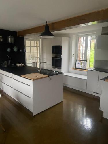 une cuisine avec des armoires blanches et un comptoir noir dans l'établissement Le Chatel- Entre terre et Mer- Proche Villers, à Danestal
