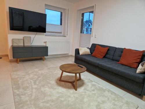 a living room with a couch and a table and a tv at Cozy Apartment: Design Superior Suite Zentral - Küche - Balkon in Cloppenburg