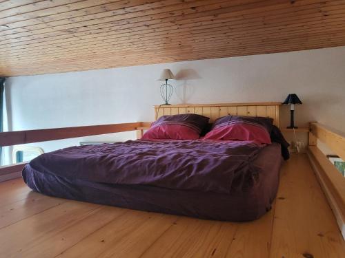un lit dans une chambre avec un plafond en bois dans l'établissement Plage des Dunes - Grand Studio ouvert avec 1 mezzanine et 1 alcôve, à Fouesnant