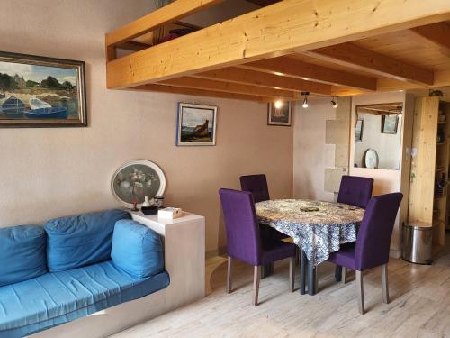 un salon avec un canapé bleu et une table dans l'établissement Plage des Dunes - Grand Studio ouvert avec 1 mezzanine et 1 alcôve, à Fouesnant
