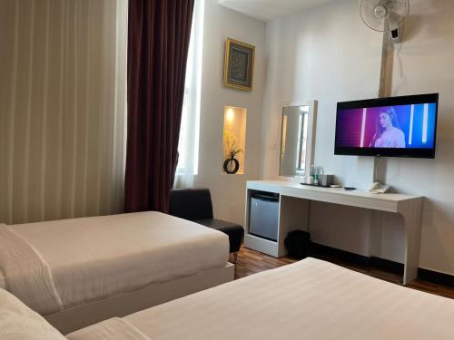 um quarto de hotel com duas camas e uma televisão de ecrã plano em DE Hotel em Phnom Penh