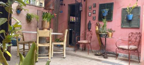 a pink building with chairs and a table with plants at Vila Santa Rosa Guest House in Ilhabela